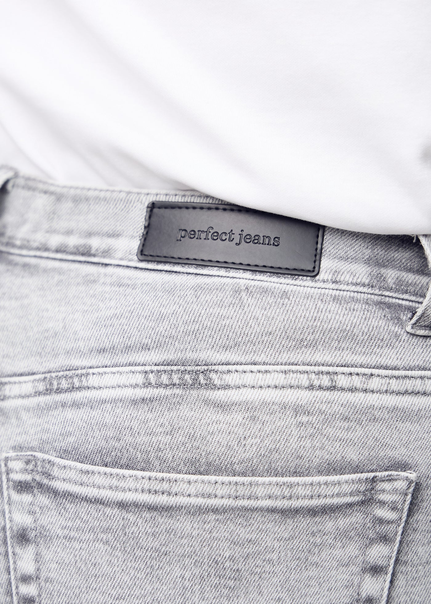 Baglommen på lysegrå denim set tæt på – tydeligt logo og tekstur vist på en plus-size model.