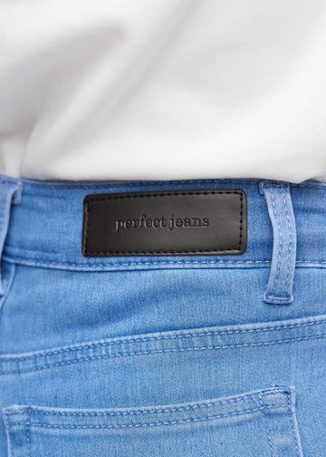 Nærbillede af blåt jeansmateriale med Perfect Jeans læderpatch bagpå i taljen.