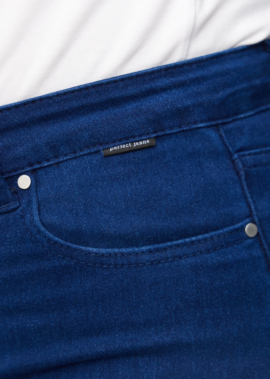Nærbillede af mørkeblåt jeansmateriale med Perfect Jeans logoetiket ved forlommekanten, på en plus-size model.