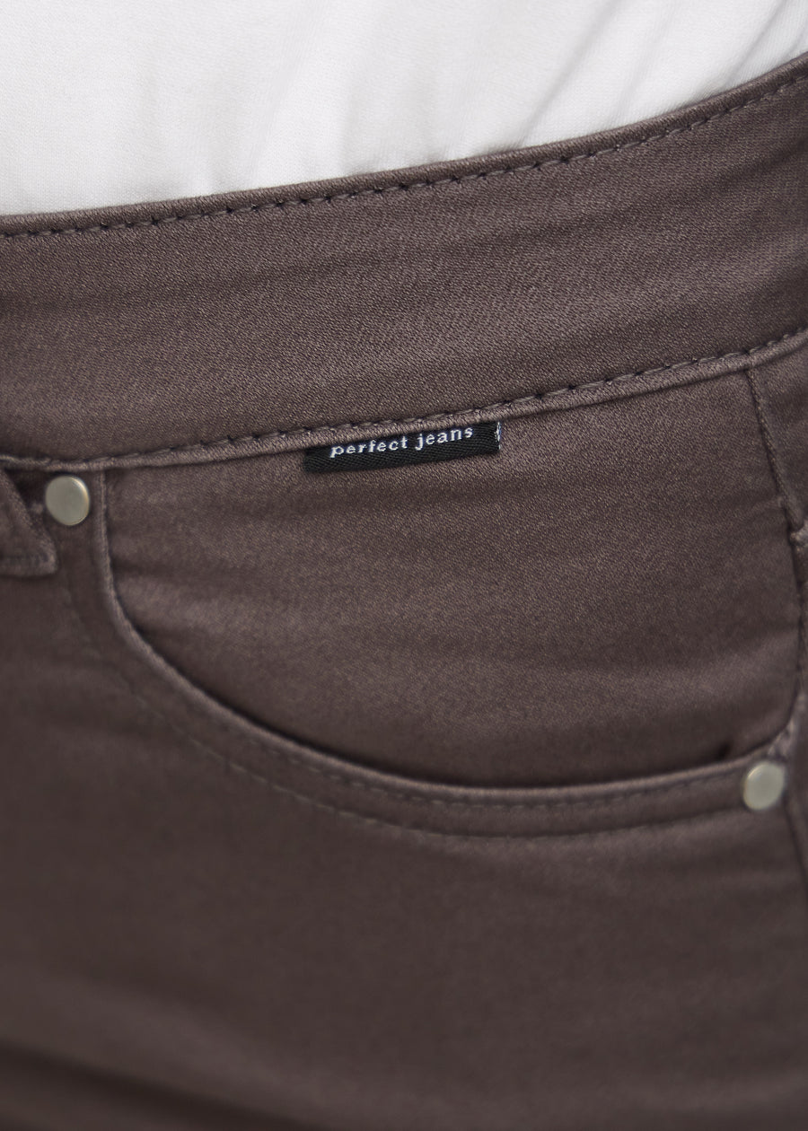 Nærbillede af gråbrunt jeansmateriale med Perfect Jeans logoetiket ved forlommekanten.