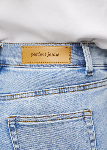 Nærbillede af lyseblå denim med Perfect Jeans læderpatch bagpå i taljen.