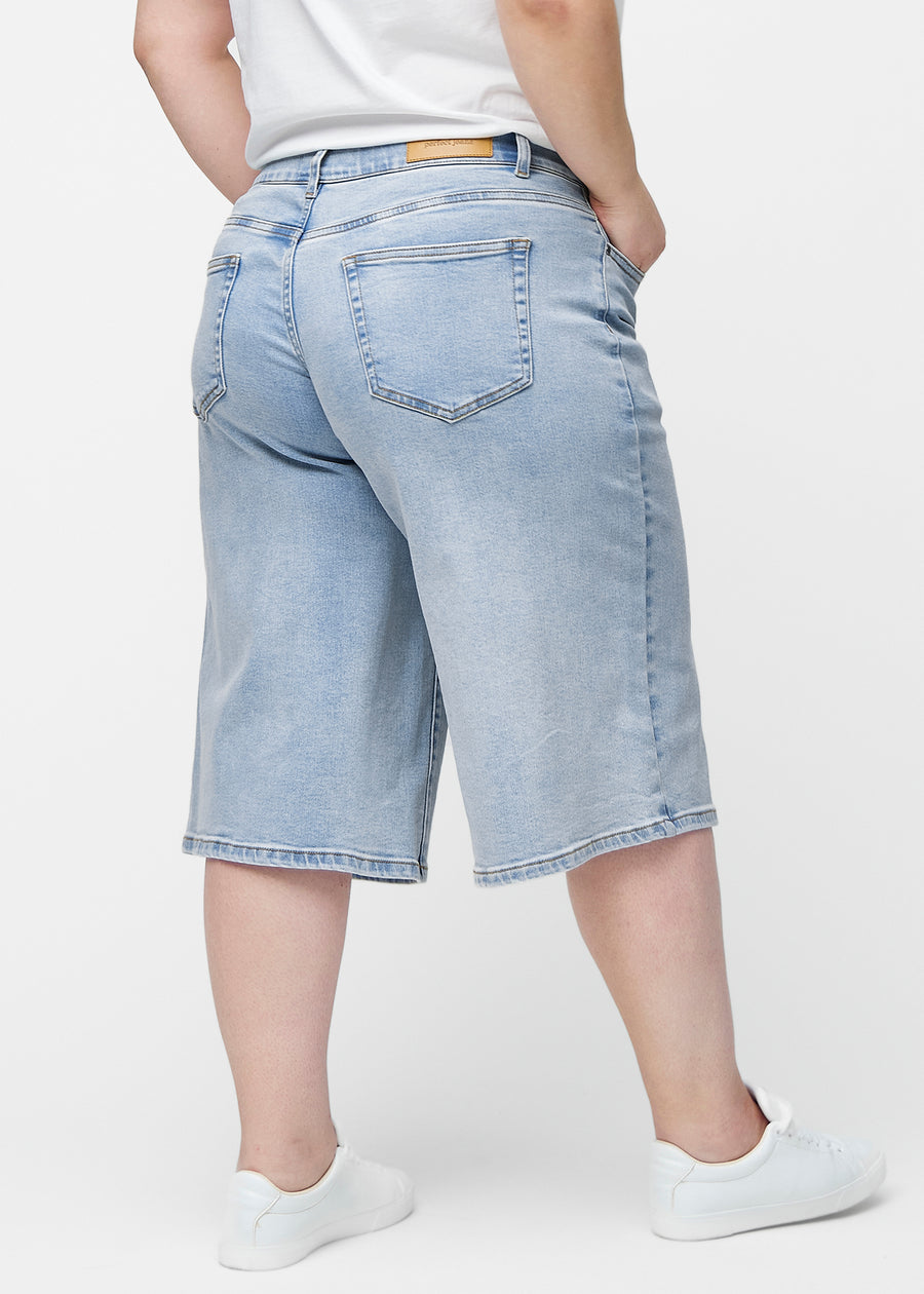 Løse, lyseblå denim capris i farven Waves set bagfra på plus-size model, så pasform og længde kan ses.