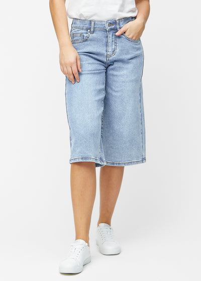 Løse, lyseblå denim capris i farven Waves, der sidder til ved hoften og falder løst ned over lårene til lige under knæet, set forfra.