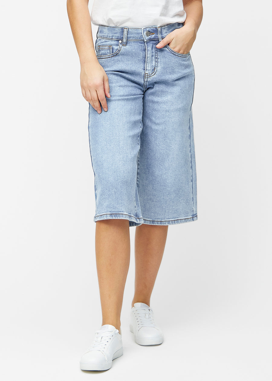 Løse, lyseblå denim capris i farven Waves, der sidder til ved hoften og falder løst ned over lårene til lige under knæet, set forfra.