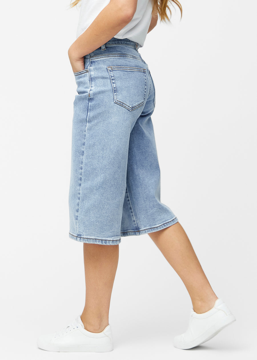 Løse, lyseblå denim capris i farven Waves set fra siden på model, hvor den brede pasform og længden til lige under knæet er synlig.