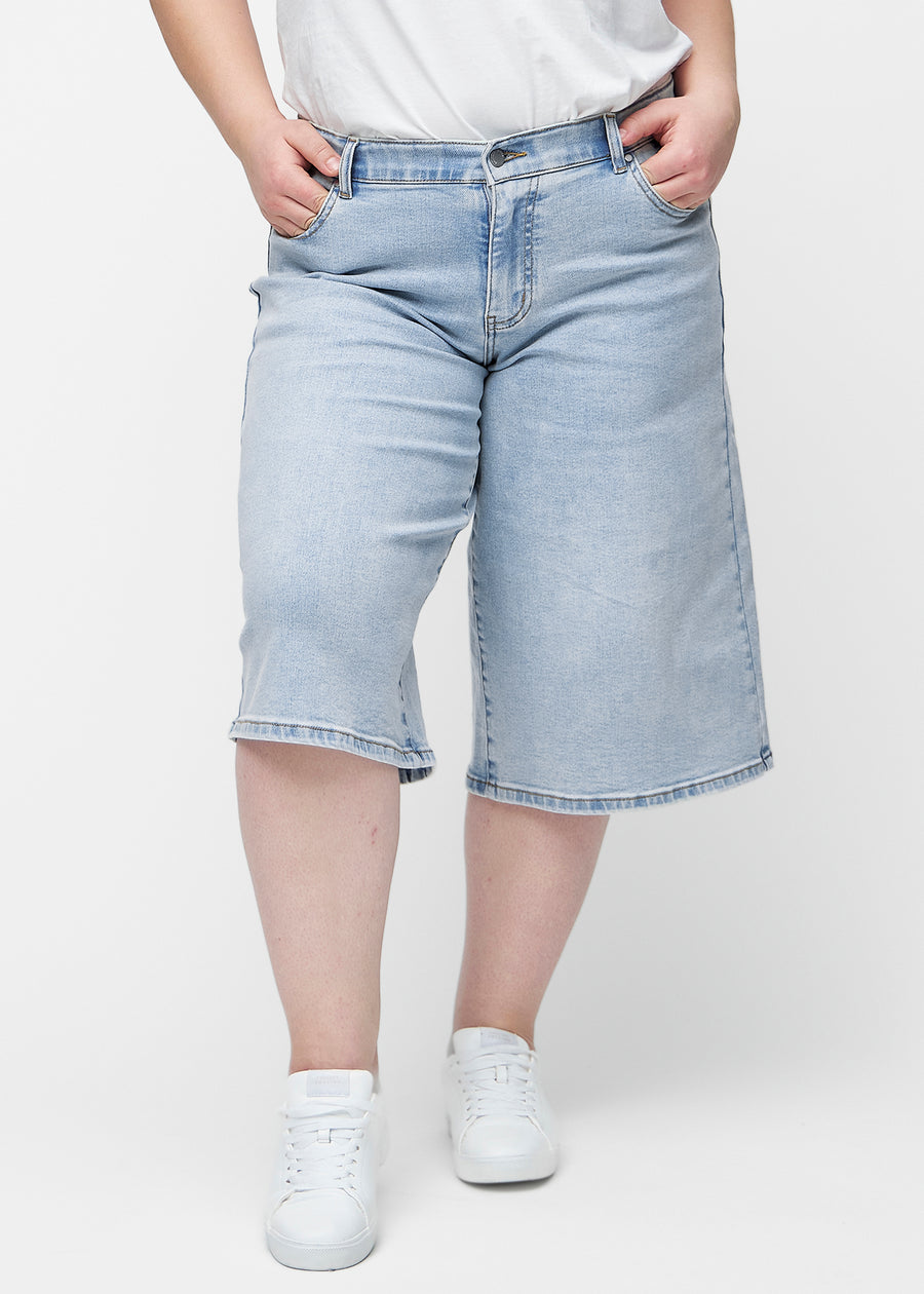 Løse, lyseblå denim capris i farven Waves set forfra på plus-size model, der sidder til ved hoften og falder løst ned.