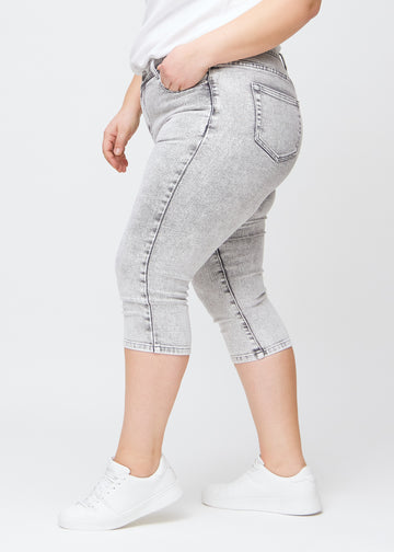 Lysegrå denim skinny capris set fra siden på en plus-size model.