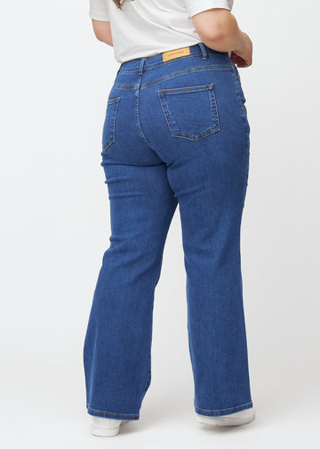 Mørkeblå mid-rise bootcut jeans i denimfarven Oceans set bagfra på en plus-size model, så man kan se hele produktet.