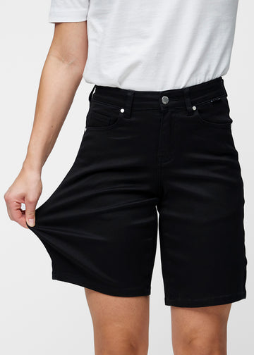 Model strækker de løse, sorte shorts i farven Ravens ved hoften for at vise materialets stretch.