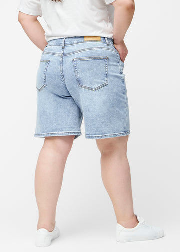 Løse, lyseblå denim shorts i farven Waves set bagfra på plus-size model, så pasform og længde kan ses.
