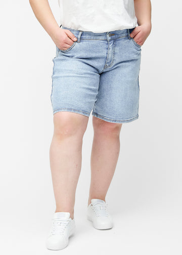 Løse, lyseblå denim shorts i farven Waves set forfra på plus-size model, der sidder til ved hoften og falder løst ned.