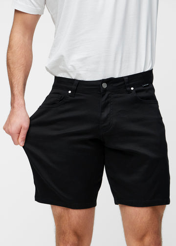 Model strækker sorte shorts til mænd i farven Ravens ved låret for at vise materialets stretch.