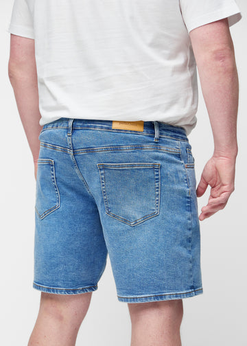 Blå denim shorts til mænd i farven Rivers set bagfra tæt på på plus-size model for at vise pasform og detaljer.