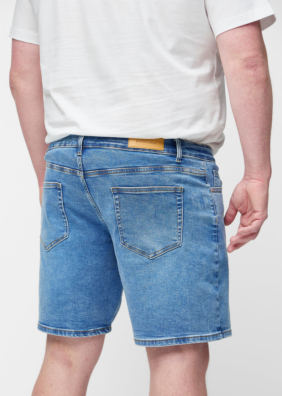 Blå denim shorts til mænd i farven Rivers set bagfra tæt på på plus-size model for at vise pasform og detaljer.