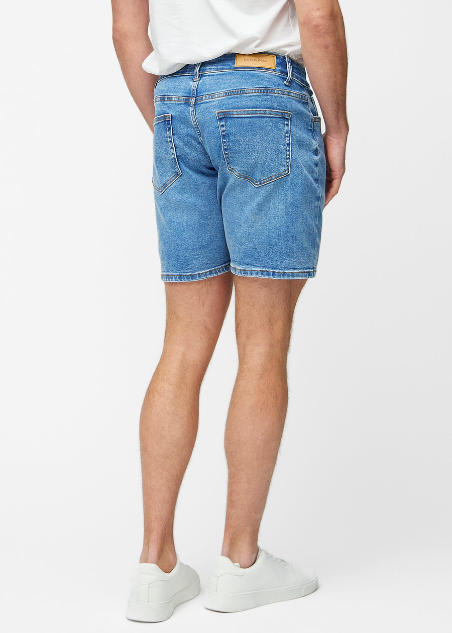 Blå denim shorts til mænd i farven Rivers set bagfra, så længden til lige over knæet og pasformen kan ses.