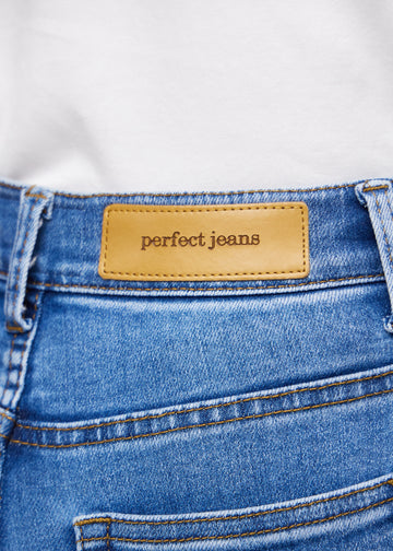 Nærbillede af blå denim med Perfect Jeans læderpatch bagpå i taljen.