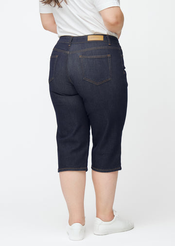 Dyb mørkeblå denim capris til kvinder i farven Midnights set bagfra på plus-size model.