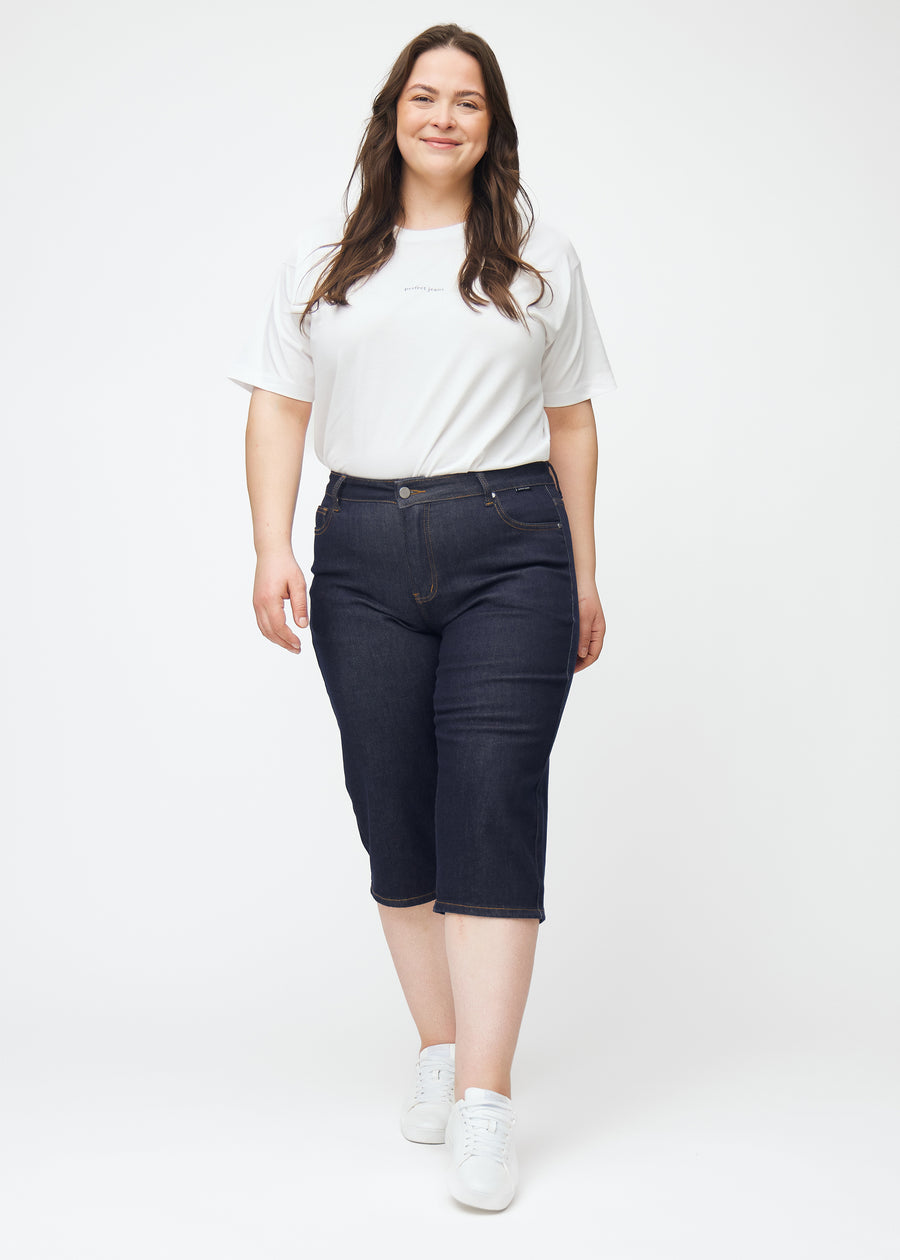 Fuldt billede af plus-size model i dyb mørkeblå denim capris til kvinder i farven Midnights med regular pasform.