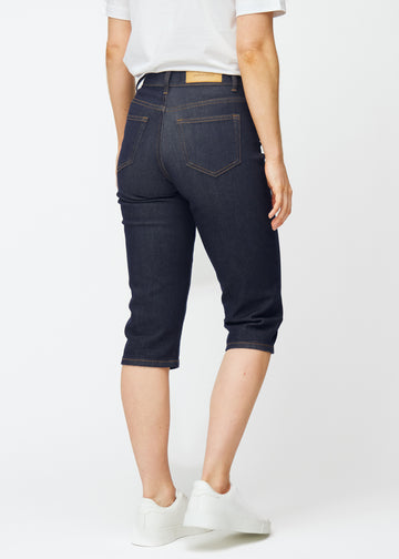 Dyb mørkeblå denim capris til kvinder i farven Midnights set bagfra, så længden til under knæet kan ses.