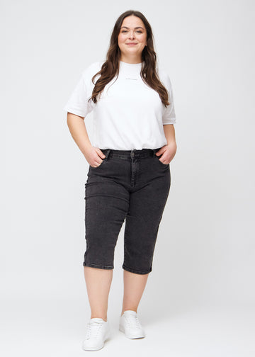 Fuldt billede af en plus-size model i mørkegrå denim regular capris.