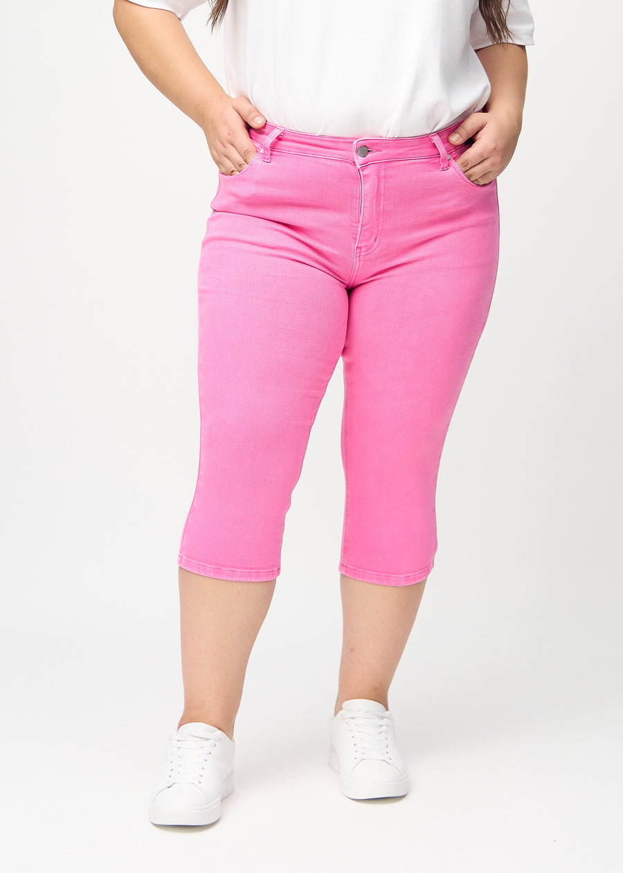 Lyserøde skinny capris, modelnavn Flamingos, som sidder tæt til benet på en plus-size model, set forfra.