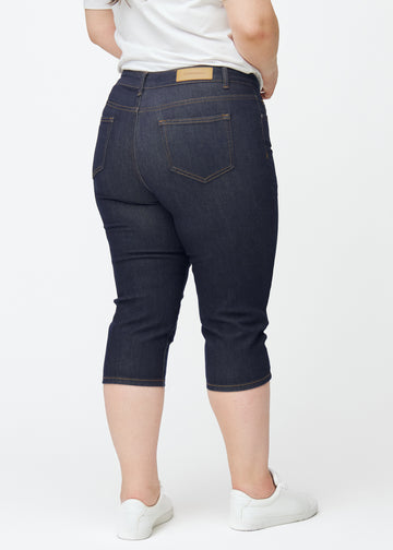 Dyb mørkeblå denim capris til kvinder i farven Midnights set bagfra på plus-size model.