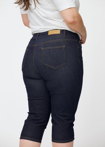 Dyb mørkeblå denim capris til kvinder i farven Midnights set bagfra tæt på på plus-size model.