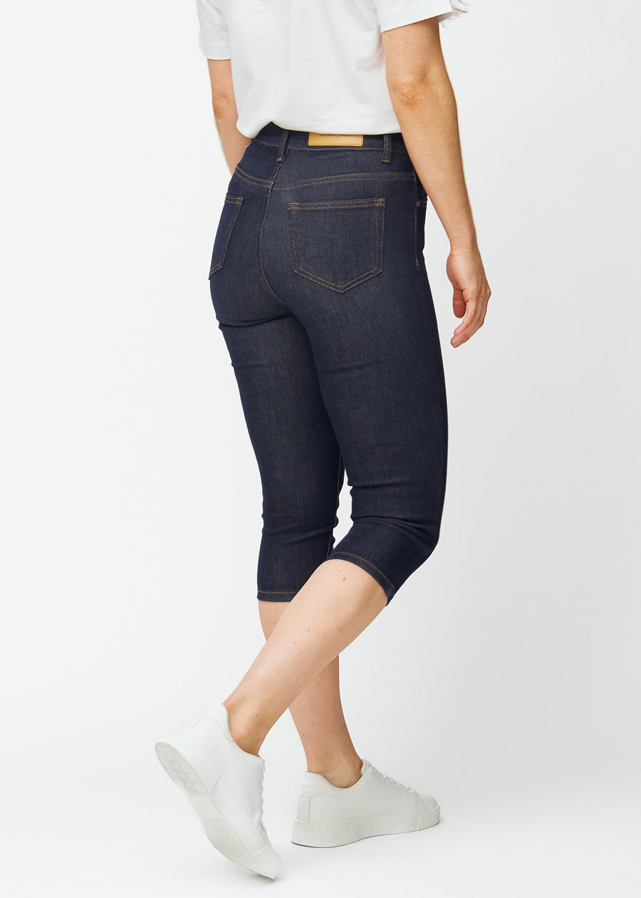 Dyb mørkeblå denim capris til kvinder i farven Midnights set bagfra, så længden til under knæet kan ses.