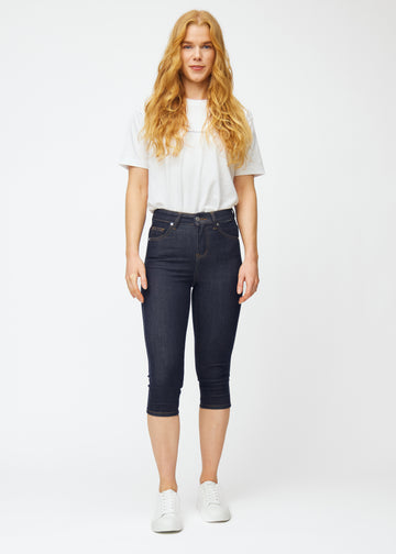 Fuldt billede af model i dyb mørkeblå denim capris til kvinder i farven Midnights med skinny pasform.