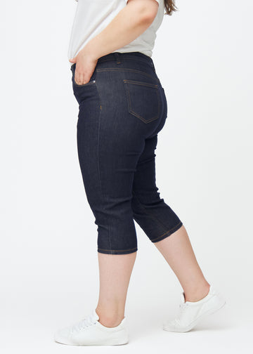 Dyb mørkeblå denim capris til kvinder i farven Midnights med skinny pasform set fra siden på plus-size model.