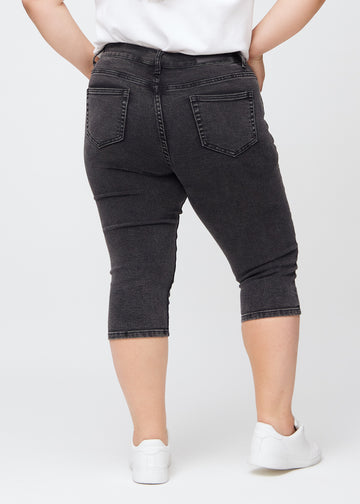 Mørkegrå denim skinny capris set bagfra på en plus-size model, så man kan se hele produktet.