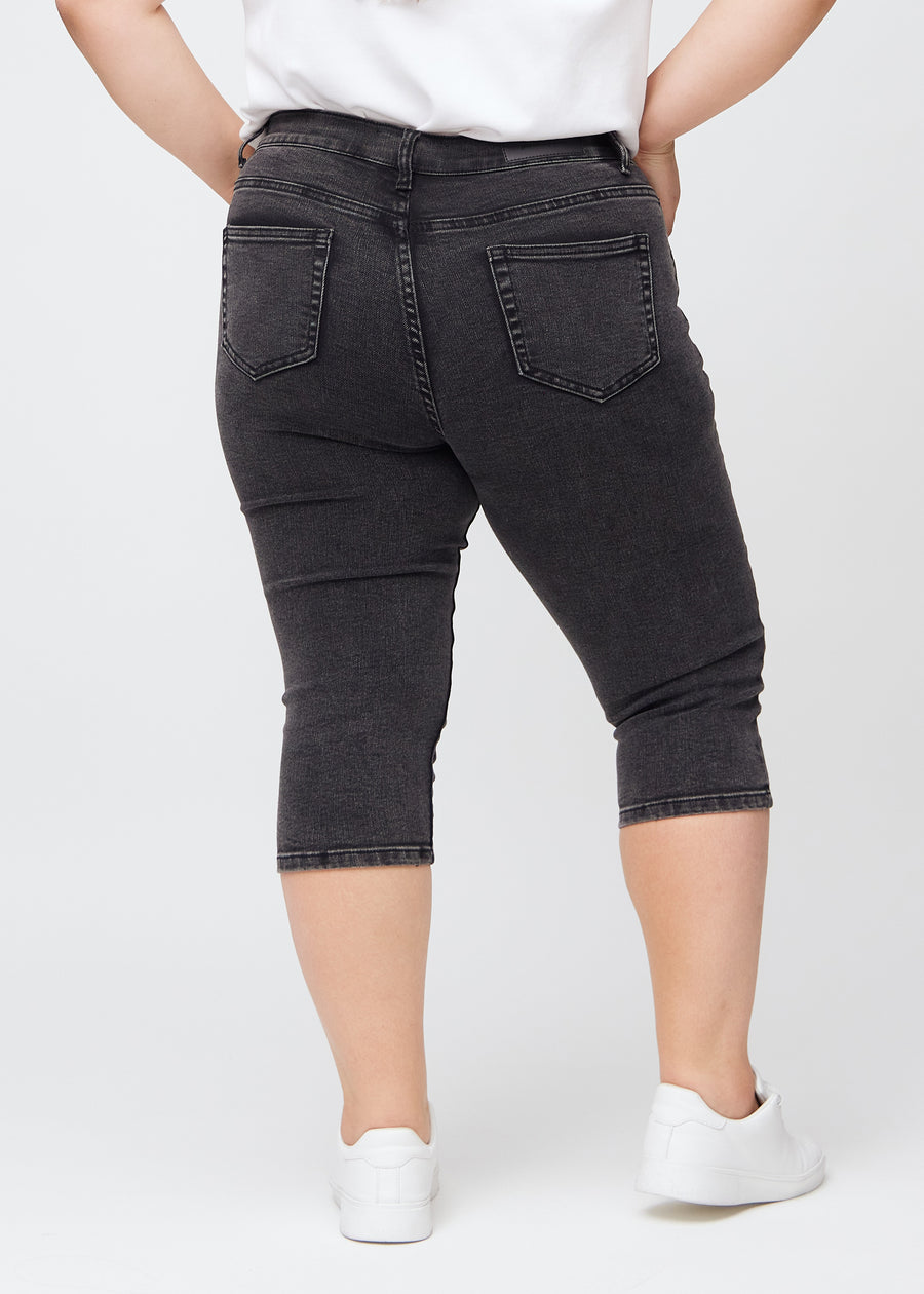 Mørkegrå denim skinny capris set bagfra på en plus-size model, så man kan se hele produktet.