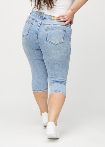 Lys denim skinny capris set bagfra på en plus-size model, så man kan se hele produktet.