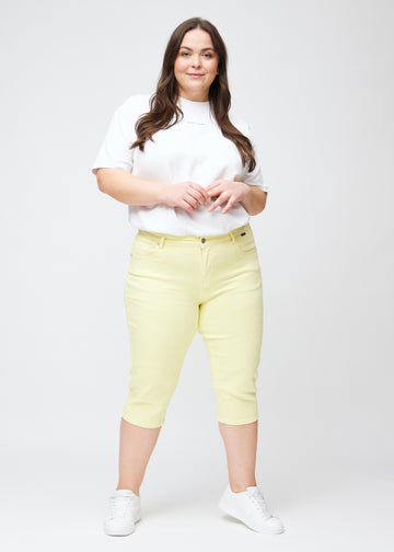 Fuldt billede af plus-size model i lysegule slim capris.
