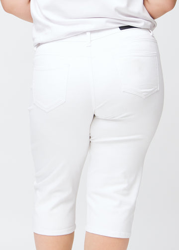 Tæt billede af bagdelen på en plus-size model i hvide slim capris – detaljefokus på lommer og syninger.