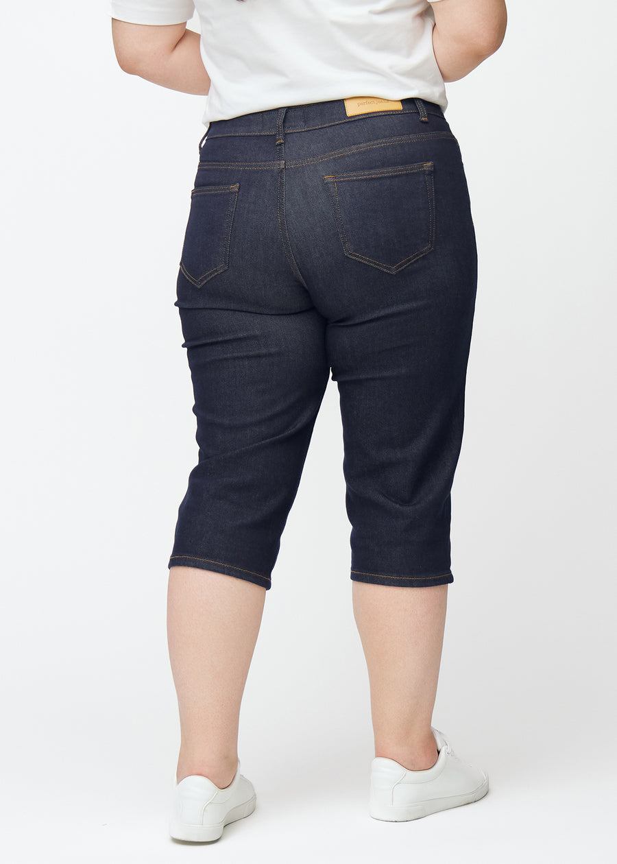 Dyb mørkeblå denim capris til kvinder i farven Midnights set bagfra på plus-size model.