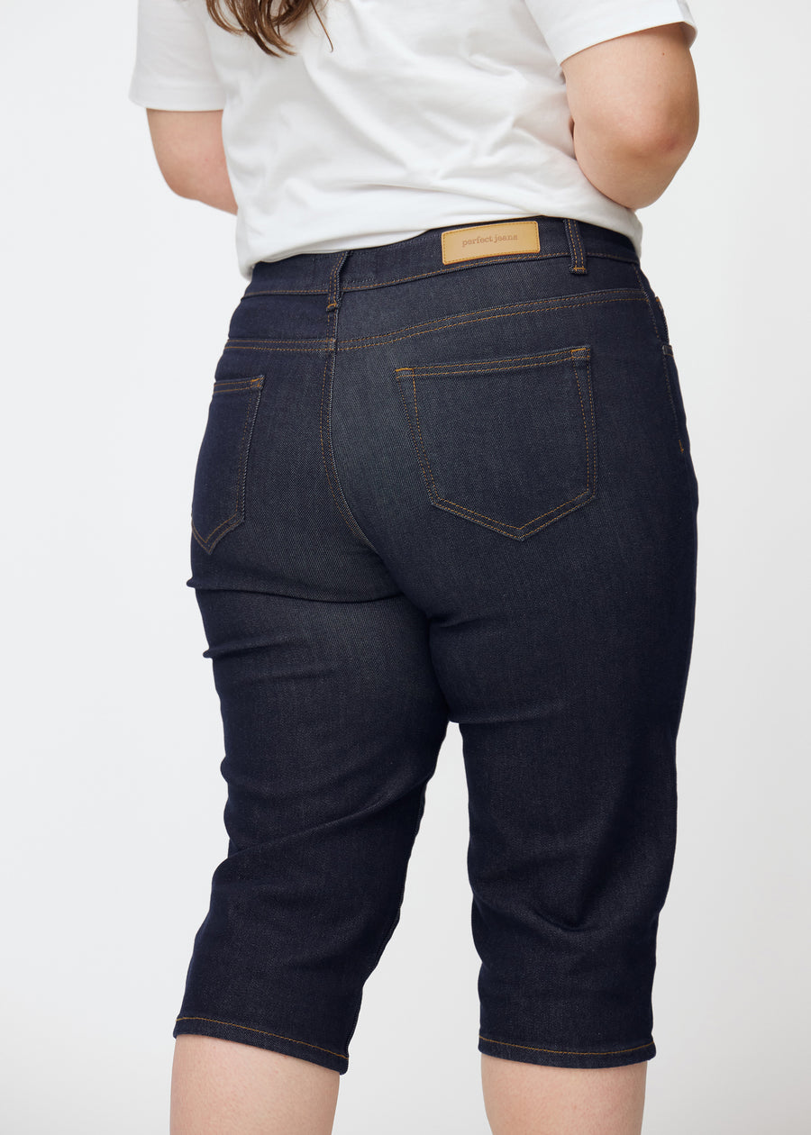 Dyb mørkeblå denim capris til kvinder i farven Midnights set bagfra tæt på på plus-size model.