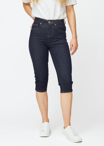 Dyb mørkeblå denim capris til kvinder i farven Midnights med slim pasform, der er figursyet fra hofte til under knæ, set forfra.