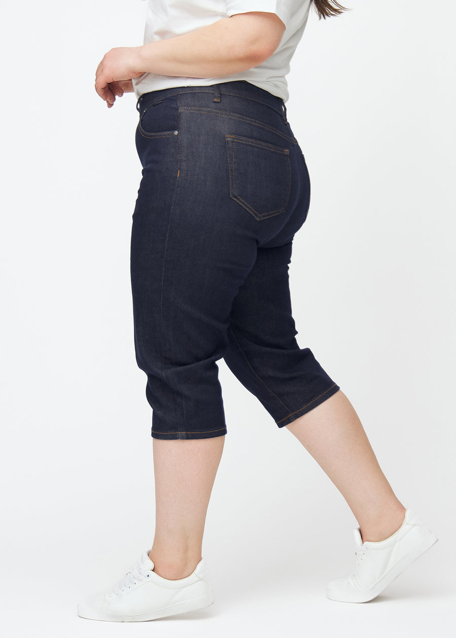Dyb mørkeblå denim capris til kvinder i farven Midnights med slim pasform set fra siden på plus-size model.