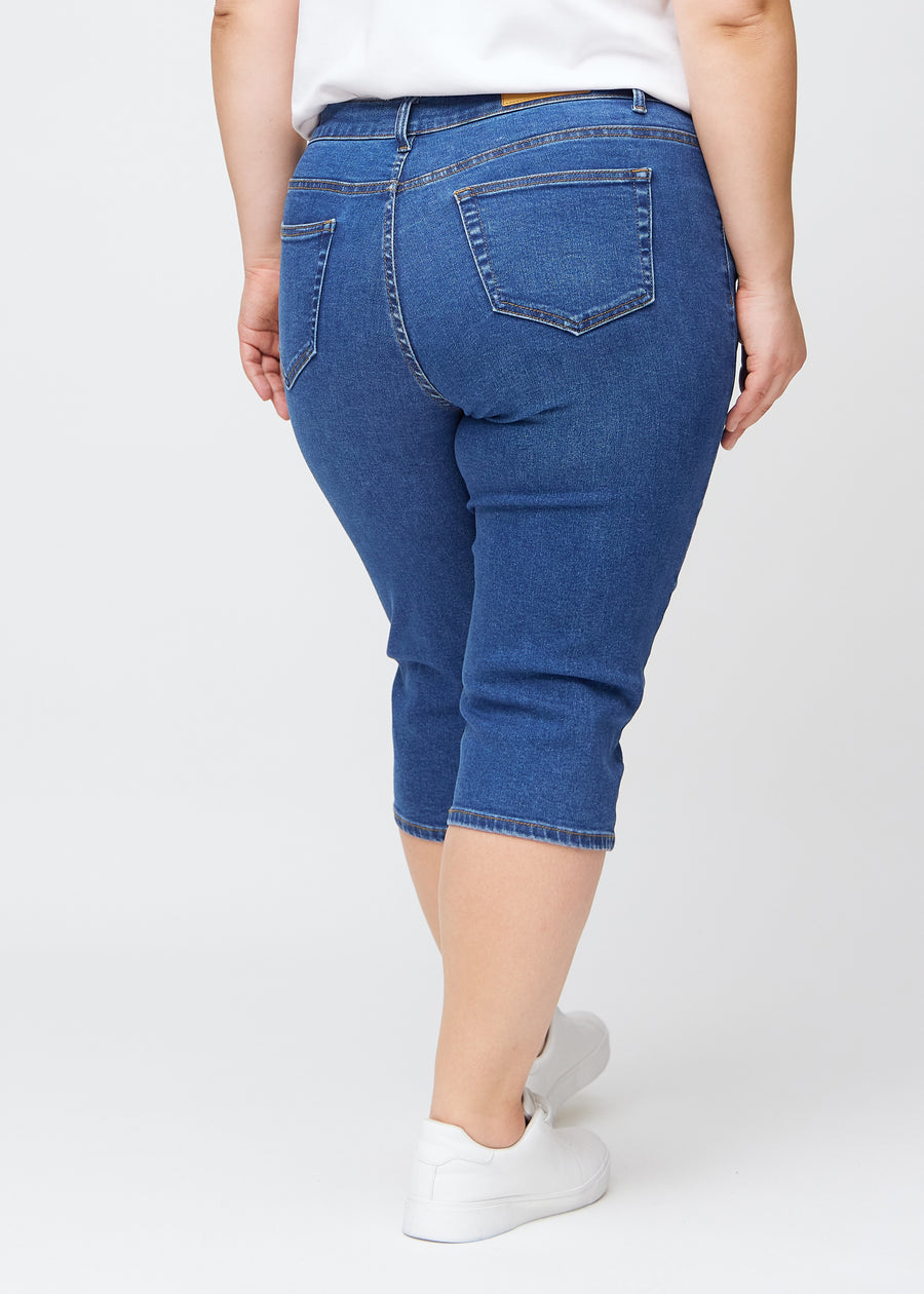 Mørkeblå denim slim capris set bagfra på en plus-size model – tydeligt billede af hele produktet og lommer.