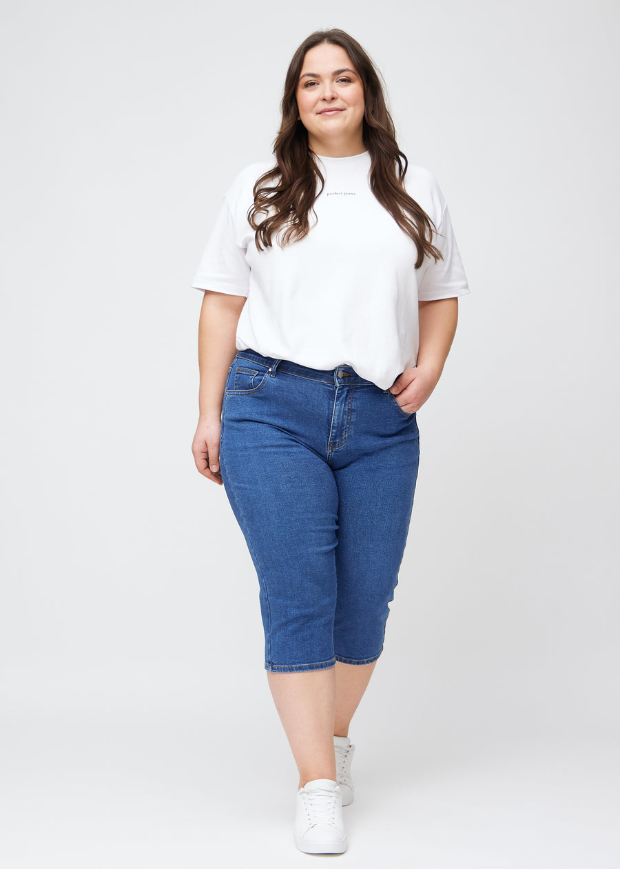 Fuldt billede af plus-size model i mørkeblå denim slim capris.