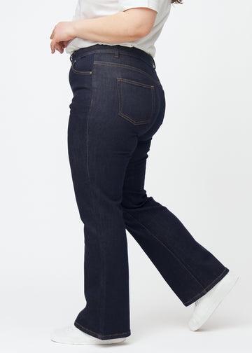 Dyb mørkeblå denim jeans til kvinder i farven Midnights med bootcut pasform set fra siden på plus-size model.