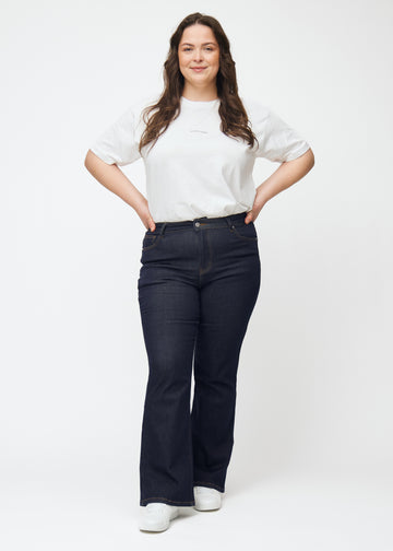 Fuldt billede af plus-size model i dyb mørkeblå denim jeans til kvinder i farven Midnights med bootcut pasform.