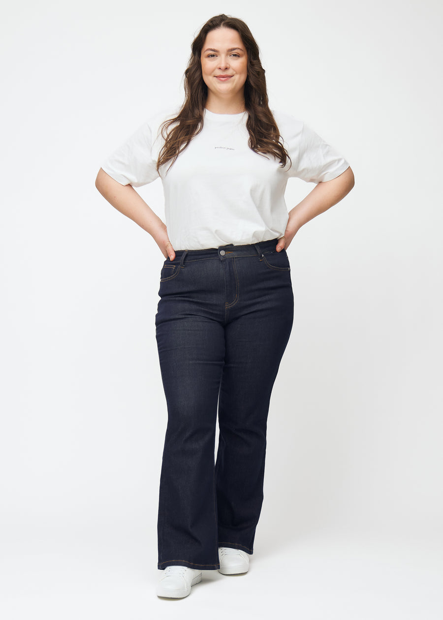 Fuldt billede af plus-size model i dyb mørkeblå denim jeans til kvinder i farven Midnights med bootcut pasform.
