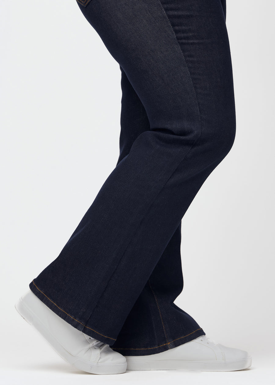 Dyb mørkeblå denim jeans til kvinder i farven Midnights med bootcut pasform set tæt på ved anklerne på plus-size model for at vise det lette svaj.