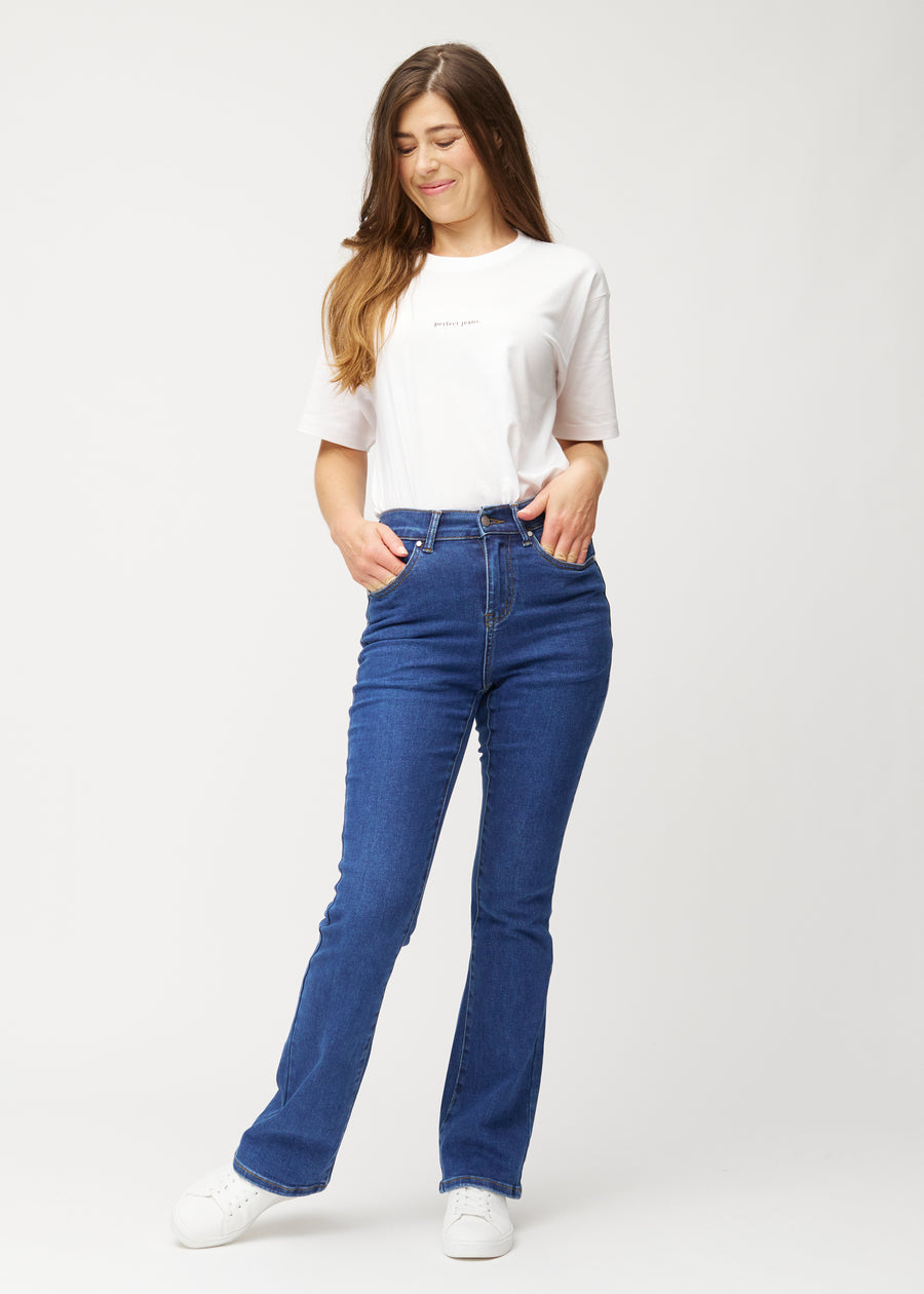 Fuldt billede af model i mørkeblå mid-rise bootcut jeans i denimfarven Oceans.