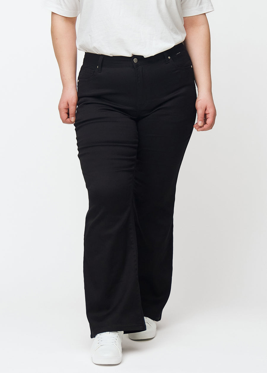 Sorte mid-rise bootcut jeans, modelnavn Ravens, som sidder tæt fra hofte til lår og har et let svaj forneden, på en plus-size model, set forfra.