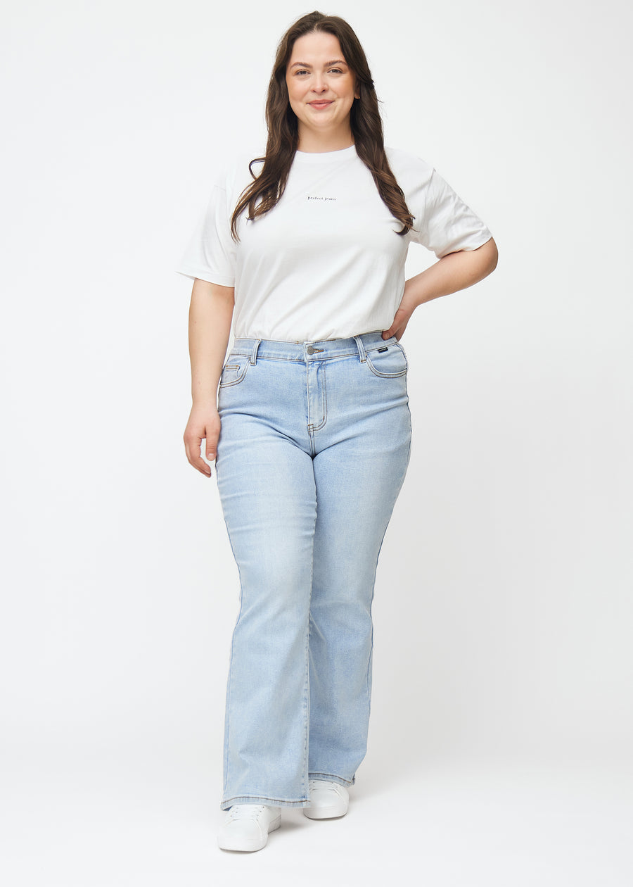 Fuldt billede af en plus-size model i lyseblå mid-rise bootcut jeans i denimfarven Waves.