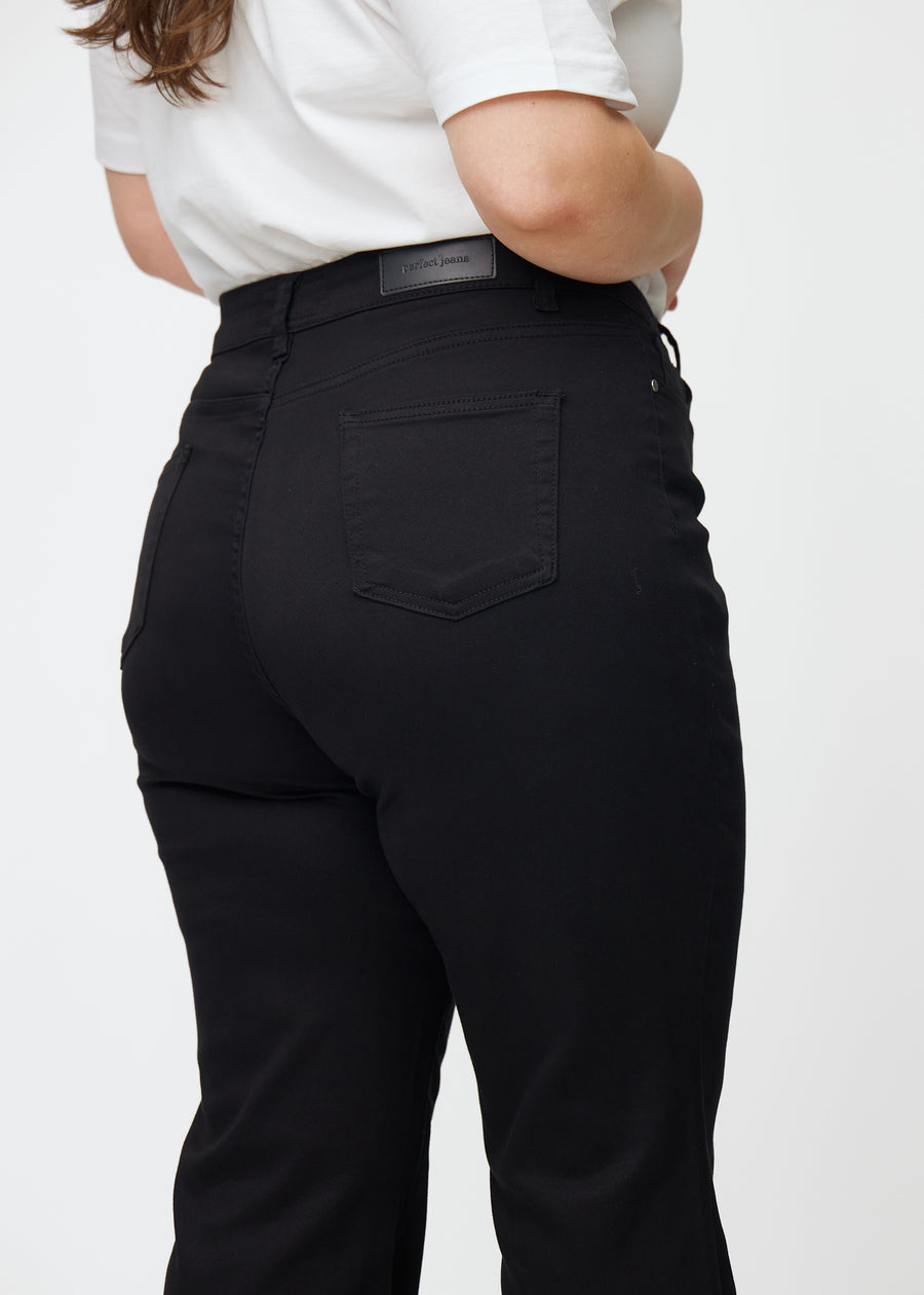 Sorte højtaljede bootcut jeans set bagfra tæt på en plus-size model for at vise detaljer.