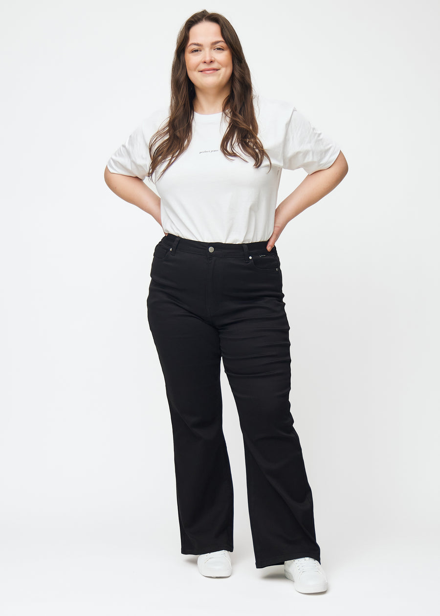 Fuldt billede af en plus-size model i sorte højtaljede bootcut jeans.